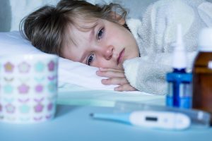 Exhausted, sick child with fever lying in bed. Healthcare and medical concept. Close up.